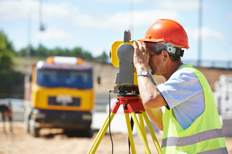 Man uses a total station to survey a construction site